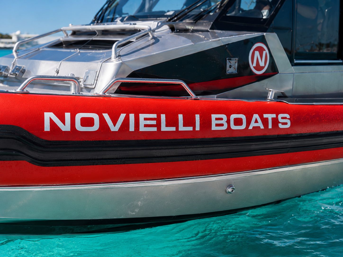 Red foam-collar hull of the Inferno 299 Fire Rescue with NOVIELLI BOATS lettering and the red circular N badge on the aluminum cabin.