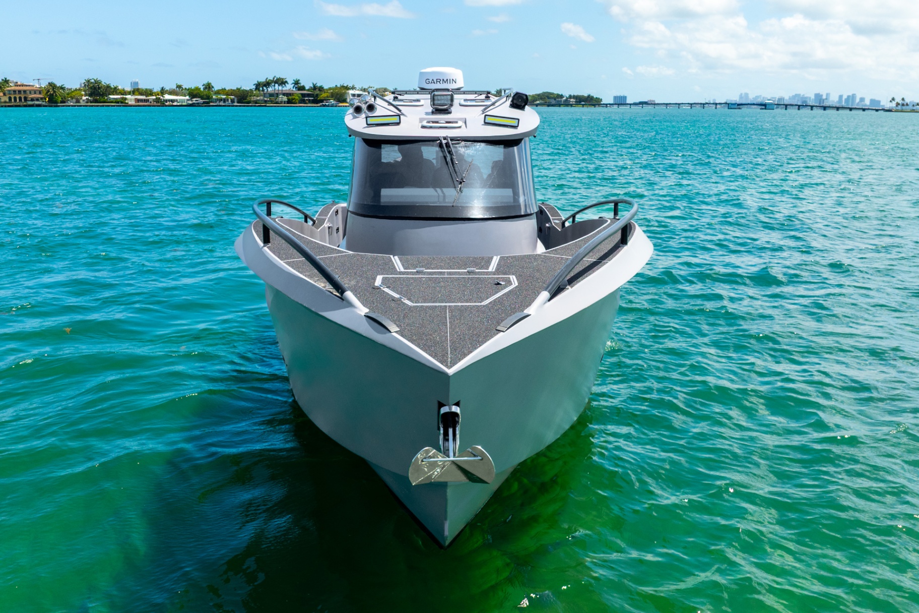 Bow-on view of the CERE 369 Signature with palm-lined coastline and city skyline in the distance.