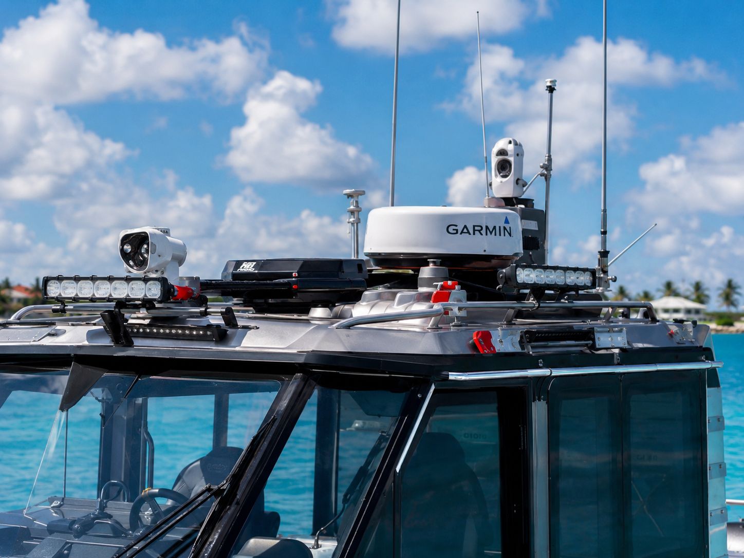 Hardtop electronics array on the Inferno 299 Fire Rescue — Garmin radar, FLIR thermal optic, LED light bars, and antenna mast against a blue sky and turquoise water.