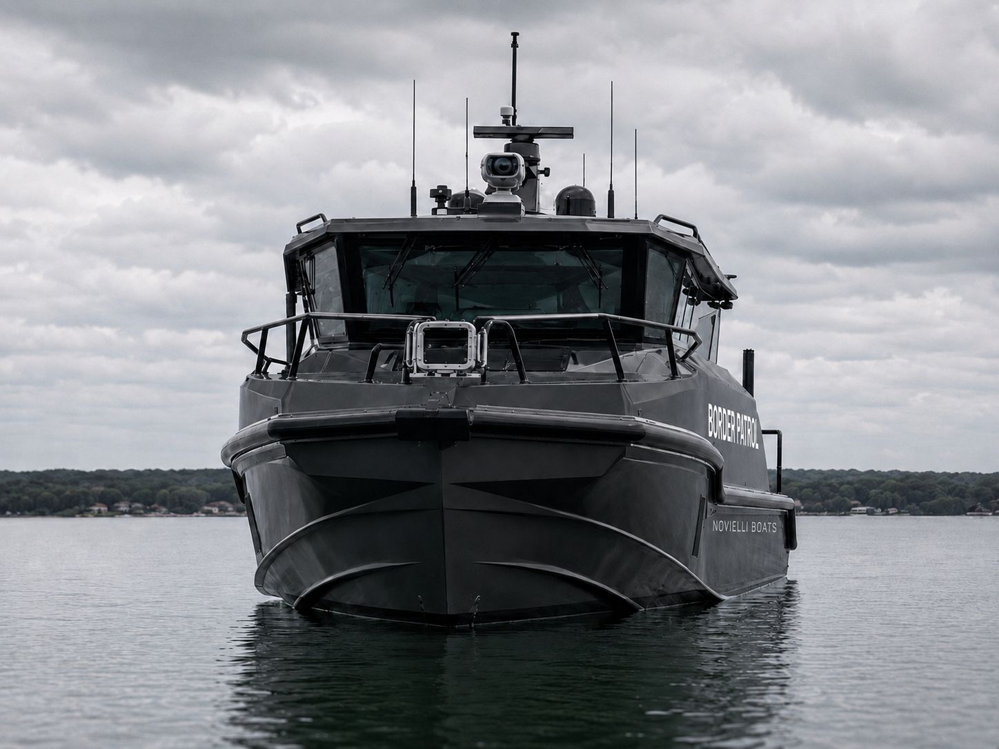 Head-on bow view of the Outlaw 559 LR catamaran showing the twin asymmetric hulls, deep-V entries, faceted pilothouse, and mast-mounted EO/IR camera.