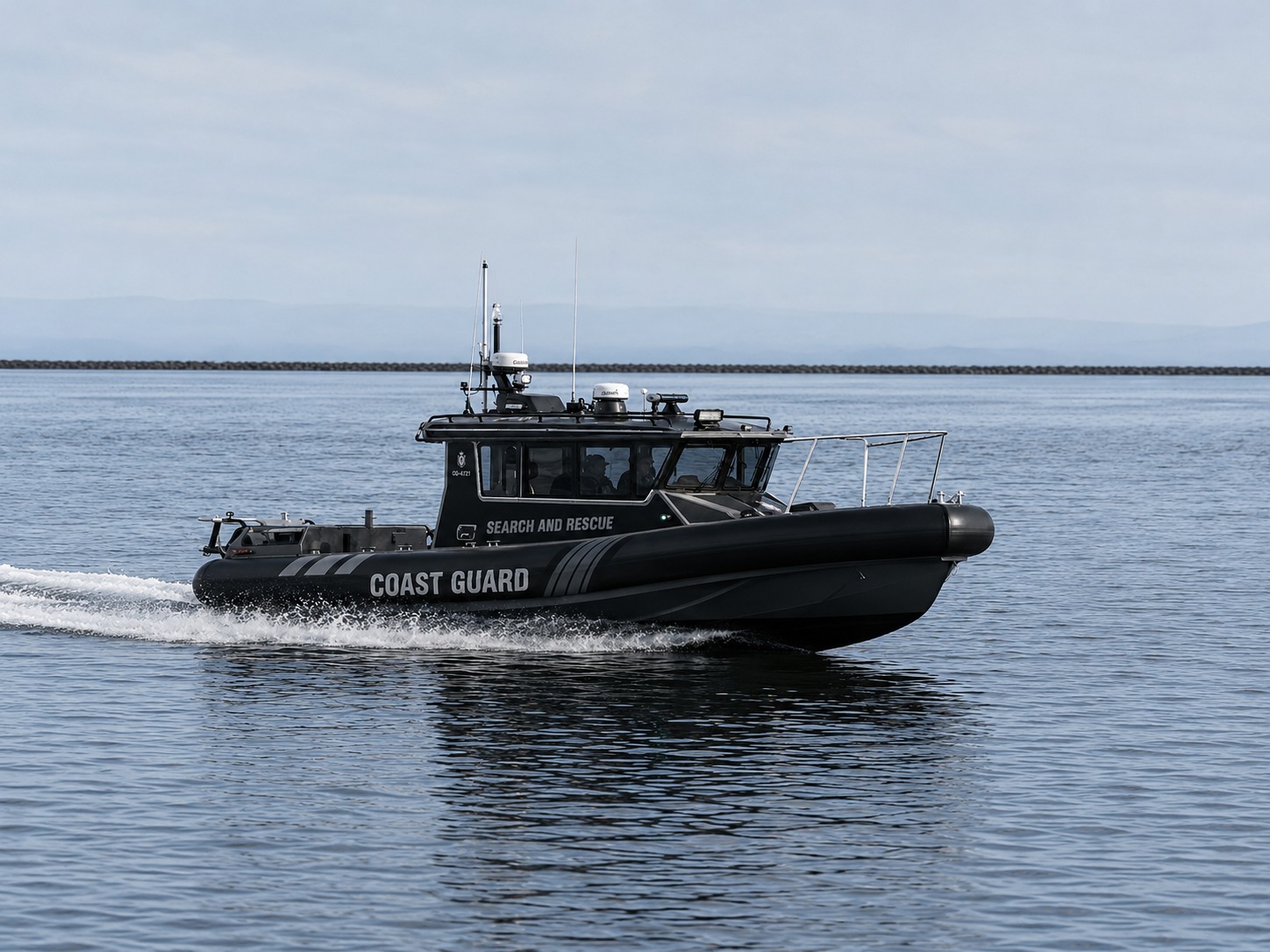 Novielli blacked-out Coast Guard search and rescue RIB cruising calm coastal water with crew at the helm.