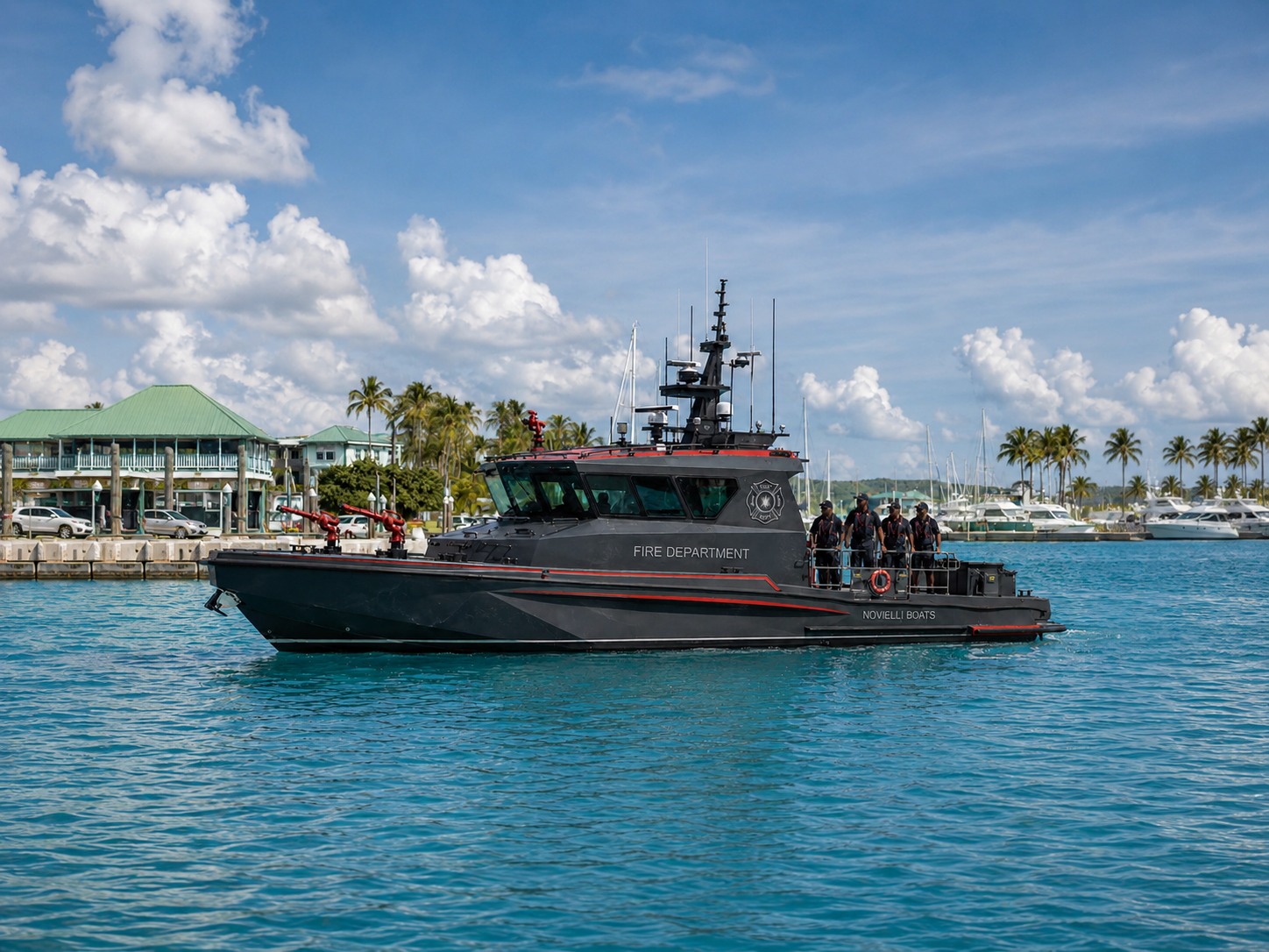 Novielli blacked-out fire department response boat with twin water cannons and red accents underway in a tropical harbor.