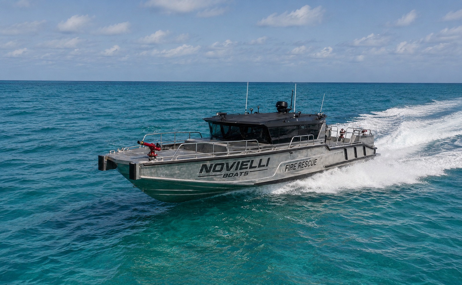 Novielli aluminum Fire Rescue vessel with blacked-out pilothouse and bow-mounted water cannon underway on turquoise tropical water.