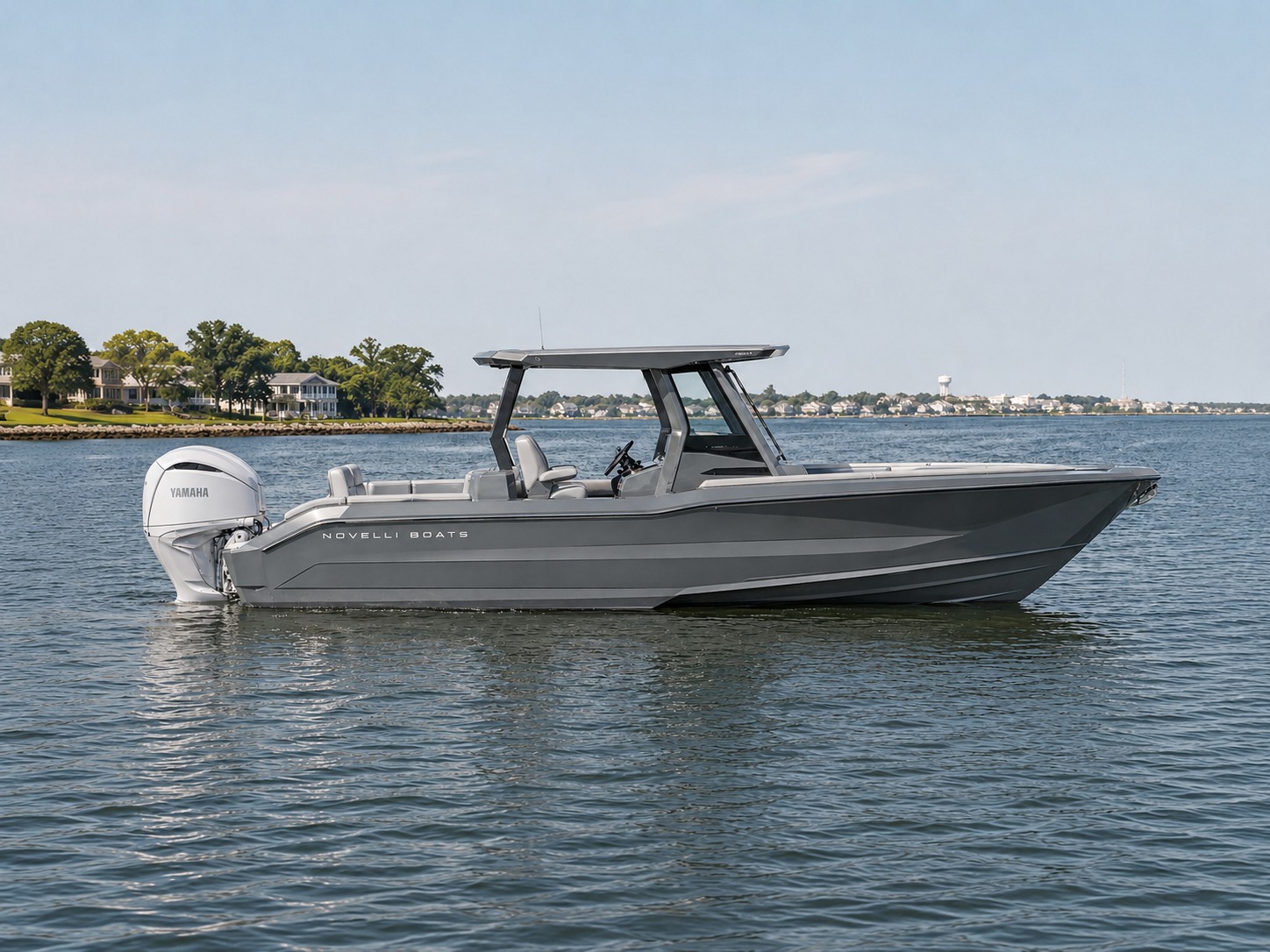 Novielli gray aluminum center console sport boat with hardtop and white Yamaha outboard sitting on calm bay water near a wooded shoreline with waterfront homes.
