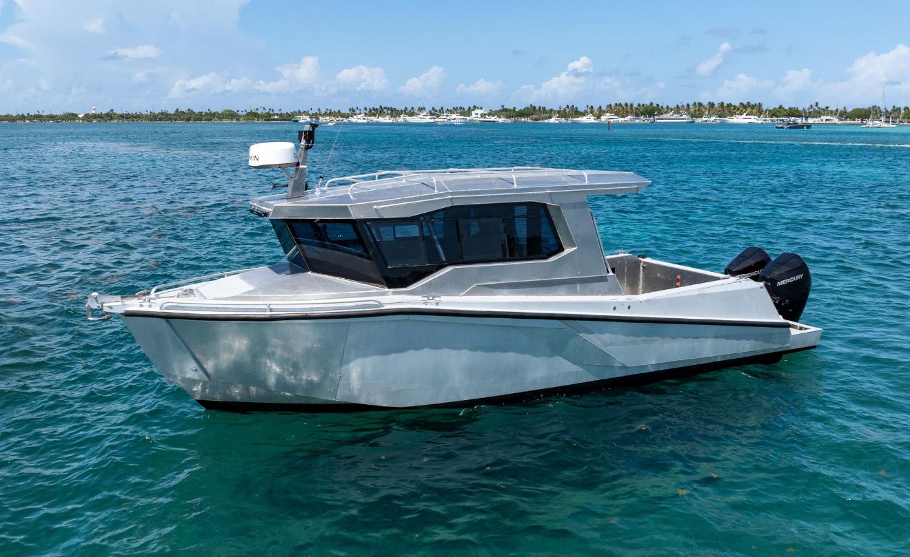 Novielli bare aluminum cabin patrol boat with Garmin radar and Mercury outboard moored on turquoise water near a palm-lined tropical marina.