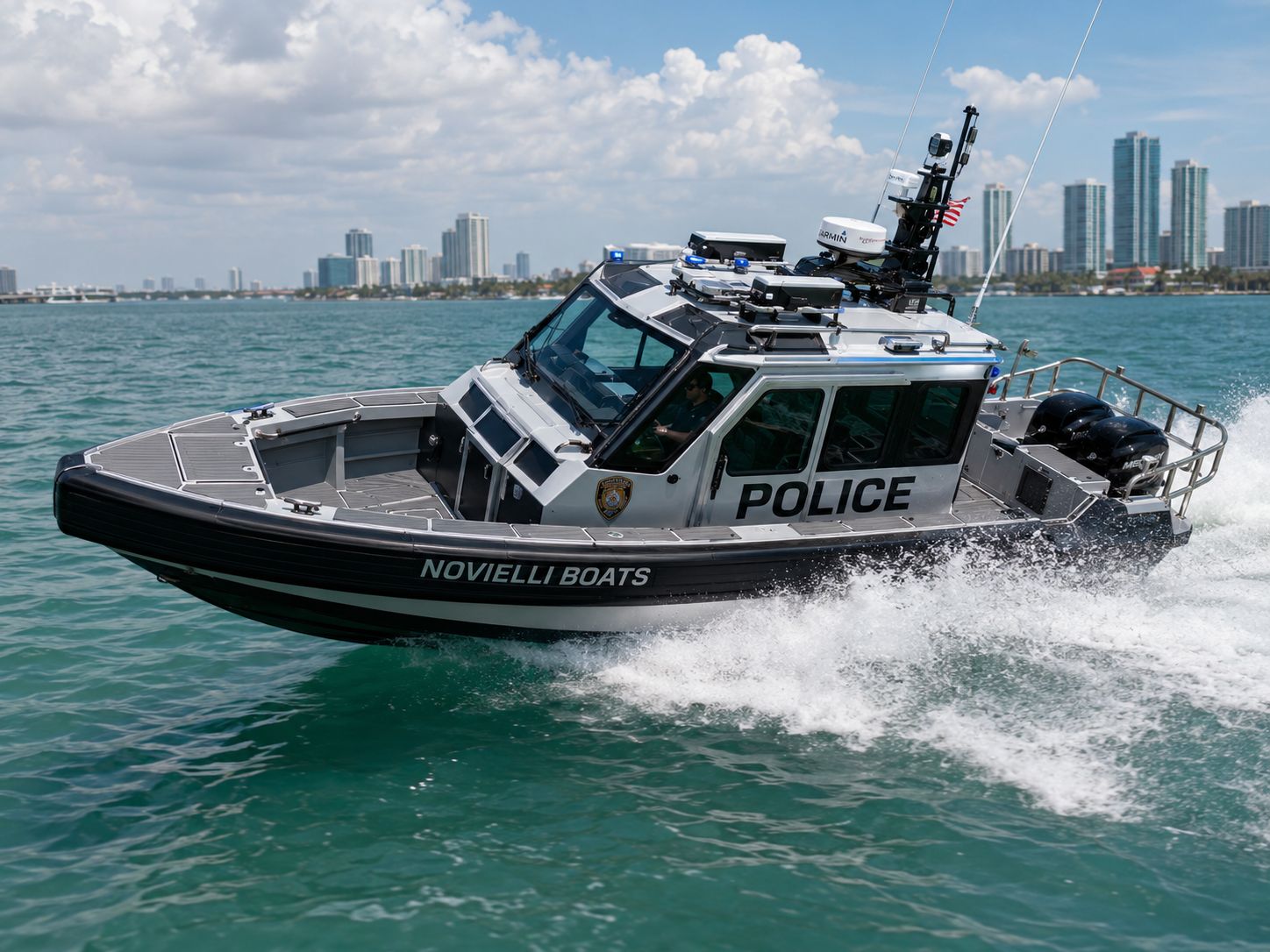 Novielli aluminum police patrol boat with cabin and twin Mercury outboards running at speed on turquoise water past the Miami skyline.